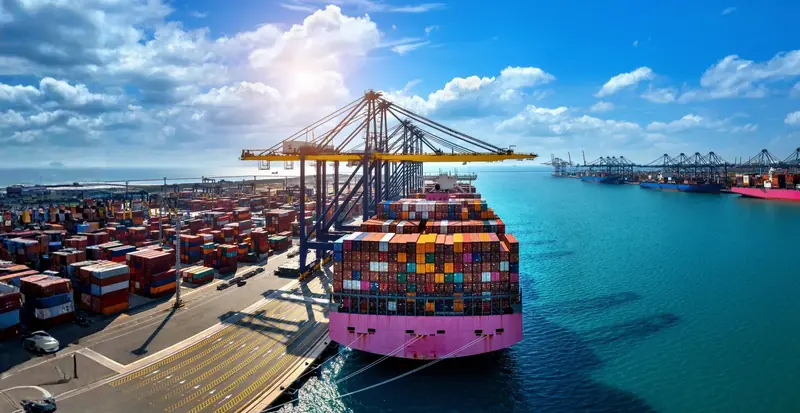 Aerial view of a laden container ship berthed under ship to shore gantry cranes at a container terminal